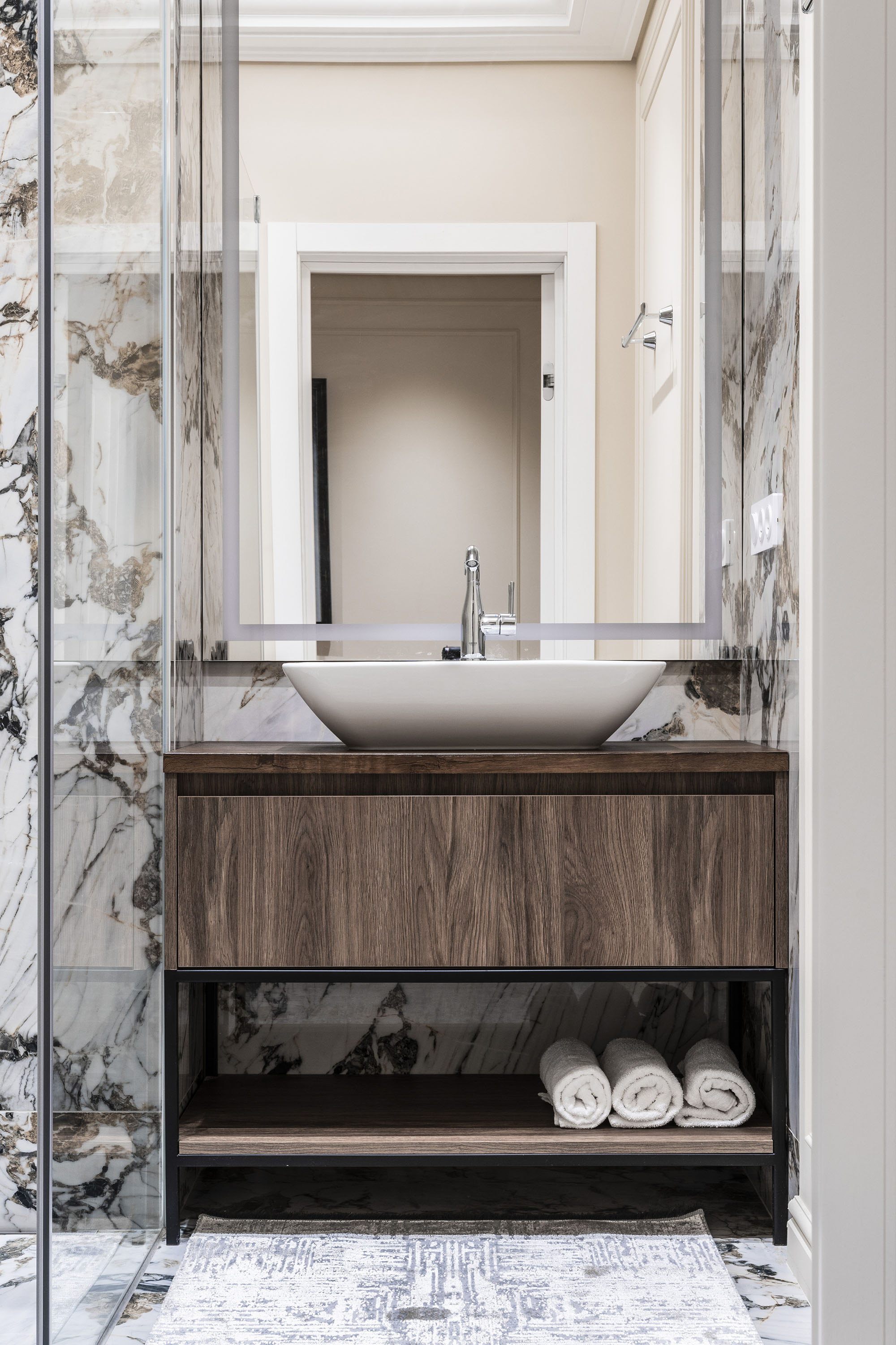 Design de interior pentru baie, cu elemente din mramura si dulap pentru prosoape.